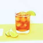 Gosling's Dark and Stormy Cocktail in a rocks glass on a yellow cutting board with limes