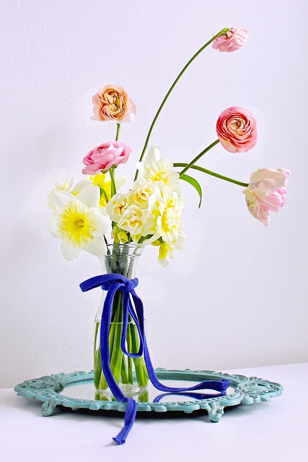Learn how to prevent a simple floral arrangement from looking cheap in this tutorial for a floral arrangement with pink peonies on a mirror centerpiece.
