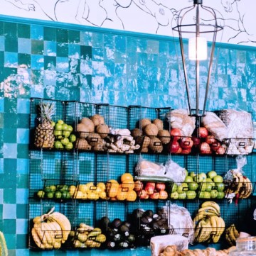 Create a cozy kitchen with Cast Iron display ideas like this teal tile wall and hanging cast iron fruit baskets