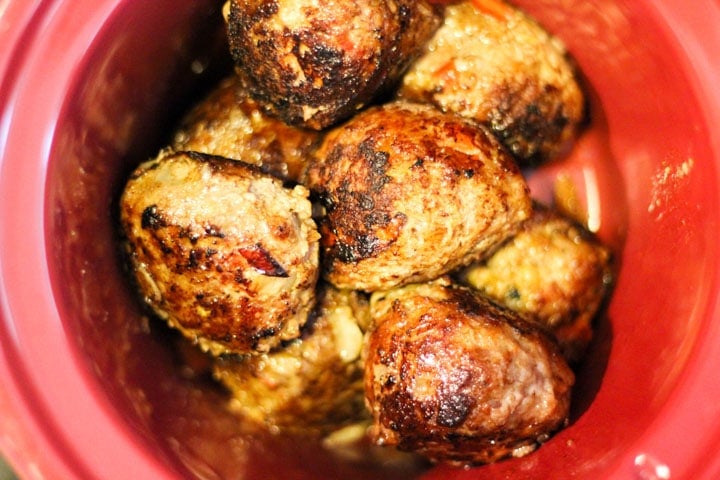 Top shot of meatballs in red slow cooker.