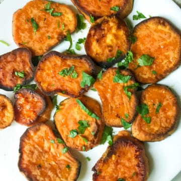 Savory roasted sweet potatoes with blue cheese crumbles on a white plate with cilantro