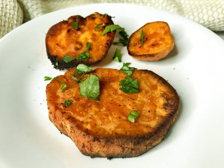 Sweet potato discs on a plate with a butter, salt, and paprika drizzle