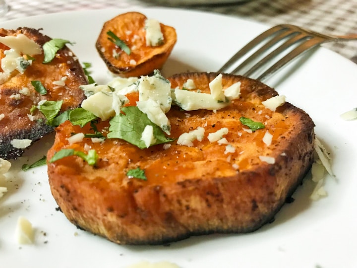 savory roasted sweet potatoes with blue cheese and cilantro on a white plate with a fork