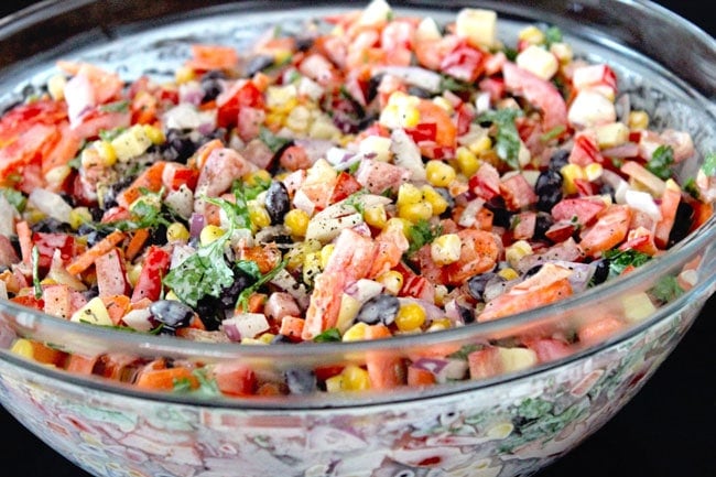 Corn, black beans, peppers and other Mexican salad ingredients in large mixing bowl