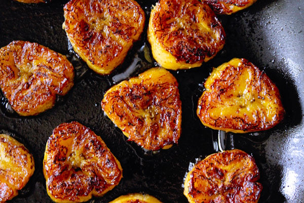 roasting fried sweet plantain slices in a pan