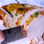 Sous vide turkey breast sliced on a cutting board with a knife