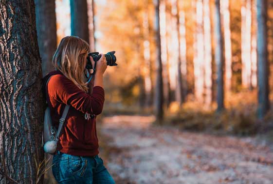 roadtrip in the fall in oregon woman taking photos in the woods while hiking