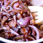Side shot of sauteed onions in a pan with a spatula.