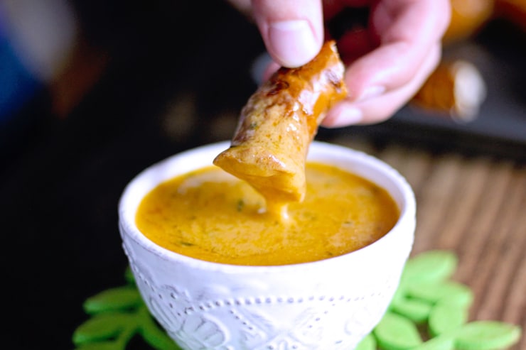 hand dipping soft pretzel in cheddar beer cheese made from scratch with real ingredients