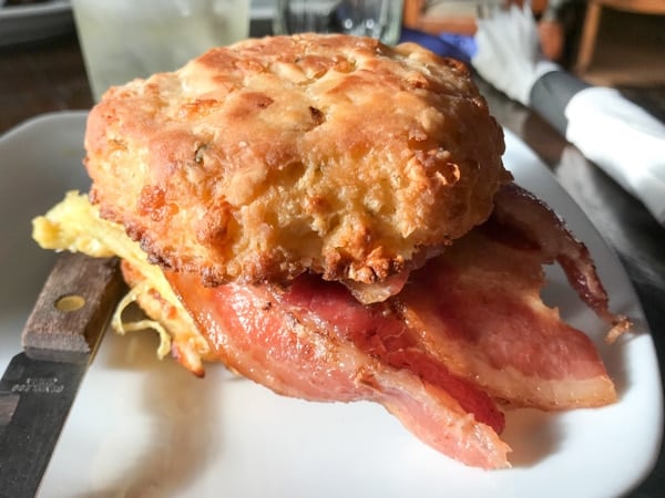 Hazel Room biscuit sandwich with bacon and scrambled egg on a white plate