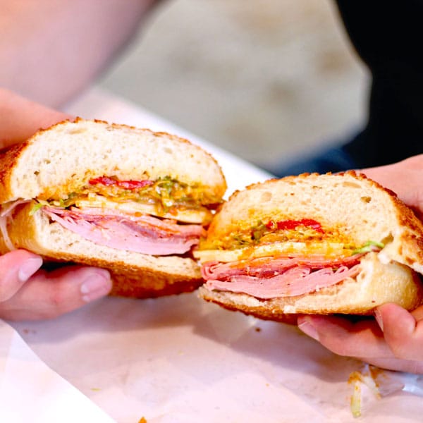 holding an Italian sandwich at The Baker's Mark