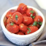 roasted cherry tomatoes with garlic on a gray kitchen towel