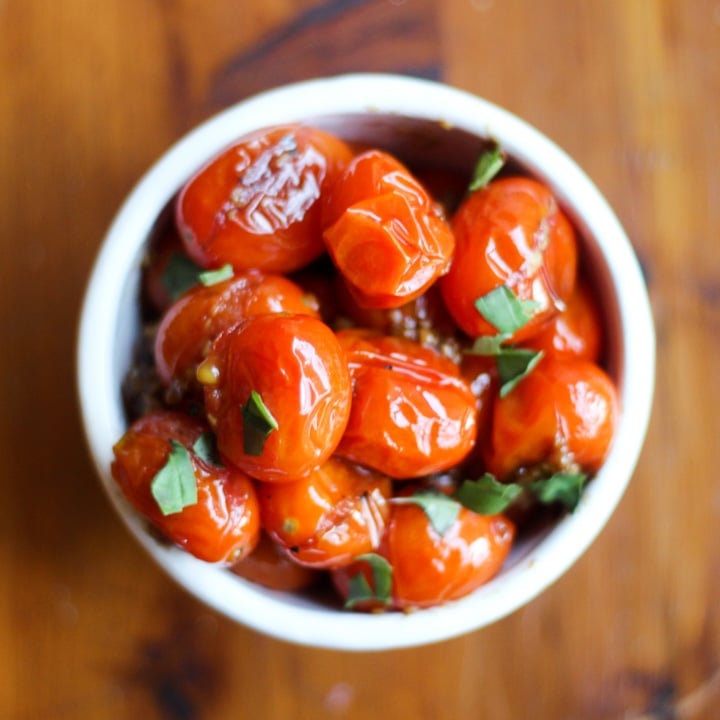 five minute side dish with roasted cherry tomatoes with garlic and fresh basil on a wood table
