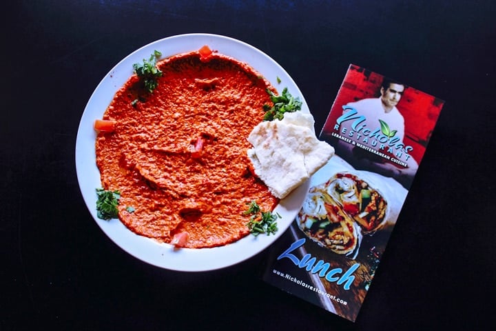 roasted red pepper and walnut hummus on a plate with pita bread and a nicholas restaurant menu