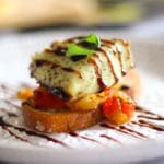 baked barramundi fish toast appetizer with red pepper and corn salsa topped with basil and balsamic glaze