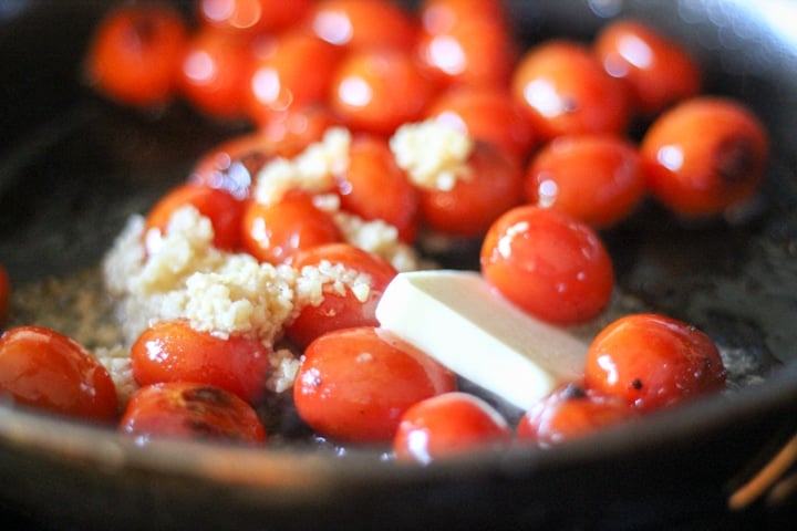 tomatoes roasting in a pan with garlic and butter