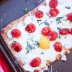 overhead shot of breakfast pizza with eggs tomatoes basil and parmesan cheese