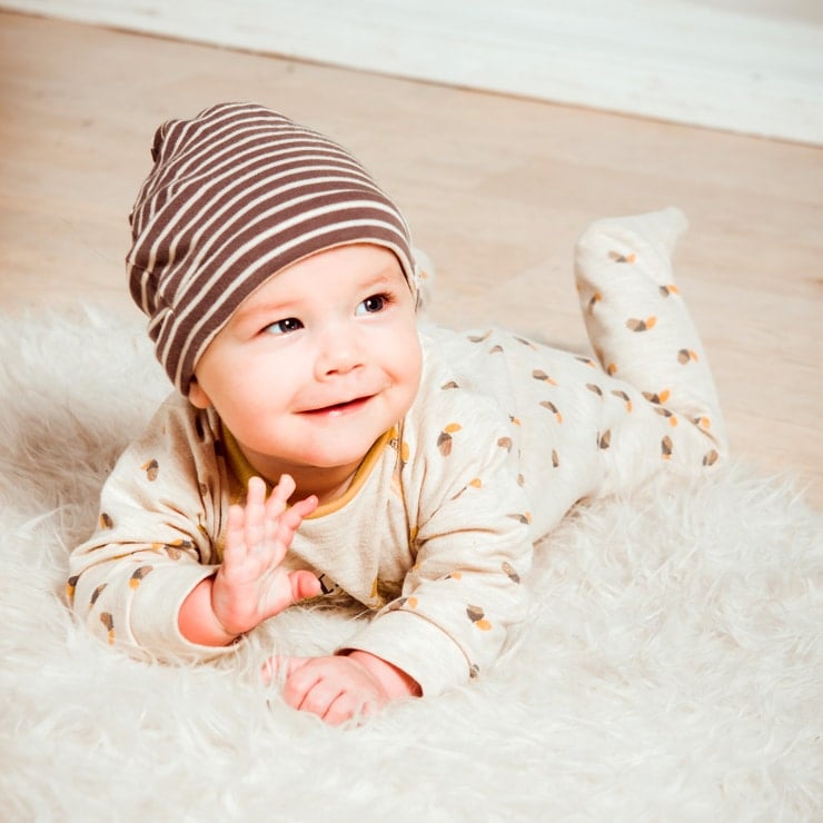 showing how to dress a baby for sleep featuring a baby sleeping in a long sleeve footed pajama and a hat for the winter