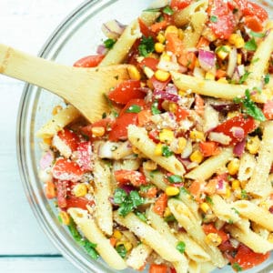 Mexican pasta salad with chili lime dressing in a serving bowl with wooden spoon