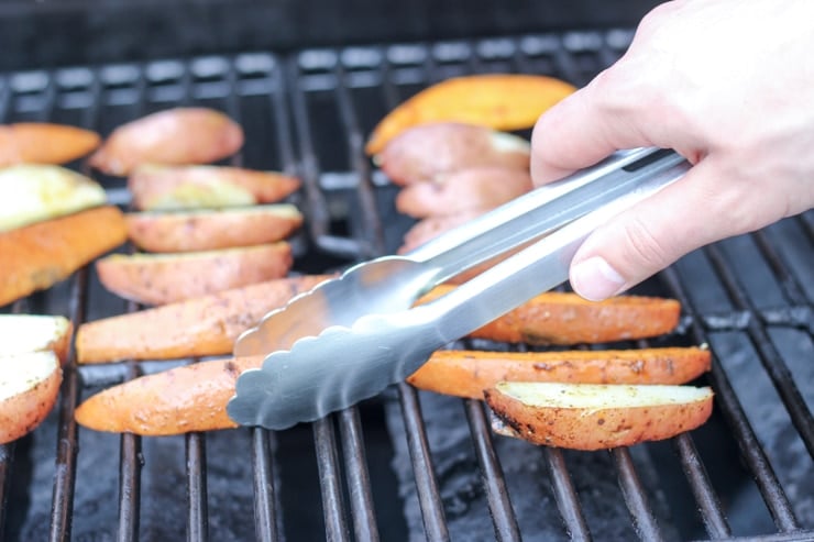 Flipping grilled potatoes with tongs