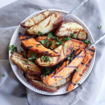 grilled potato wedges with tongs on a gray table