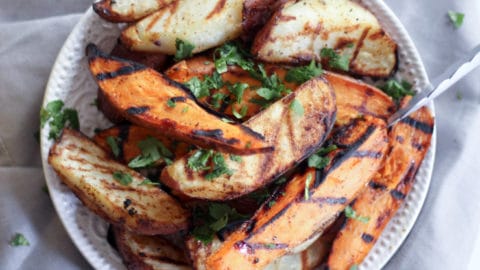 grilled potato wedges with tongs on a gray table