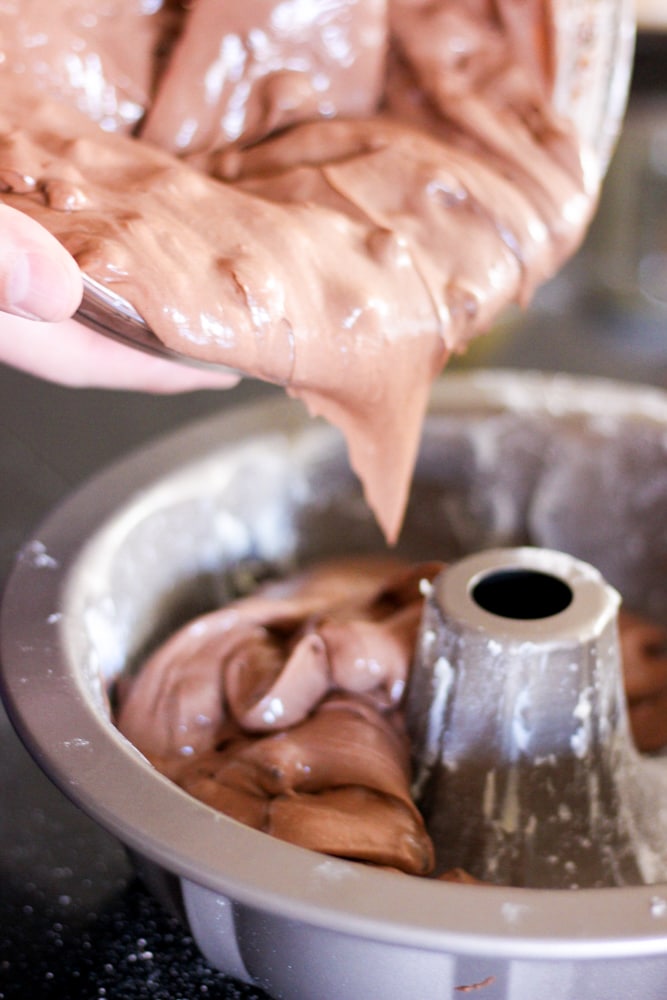 pouring chocolate cake batter into a bundt pan