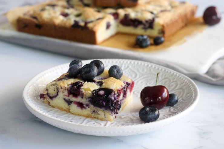 fresh blueberry and cherry cake bars on a plate with fruit