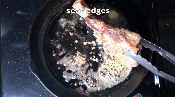 searing edges of steak in a cast iron pan