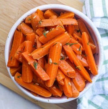 Top down shot of sauteed carrots side dish with garlic butter and herbs.