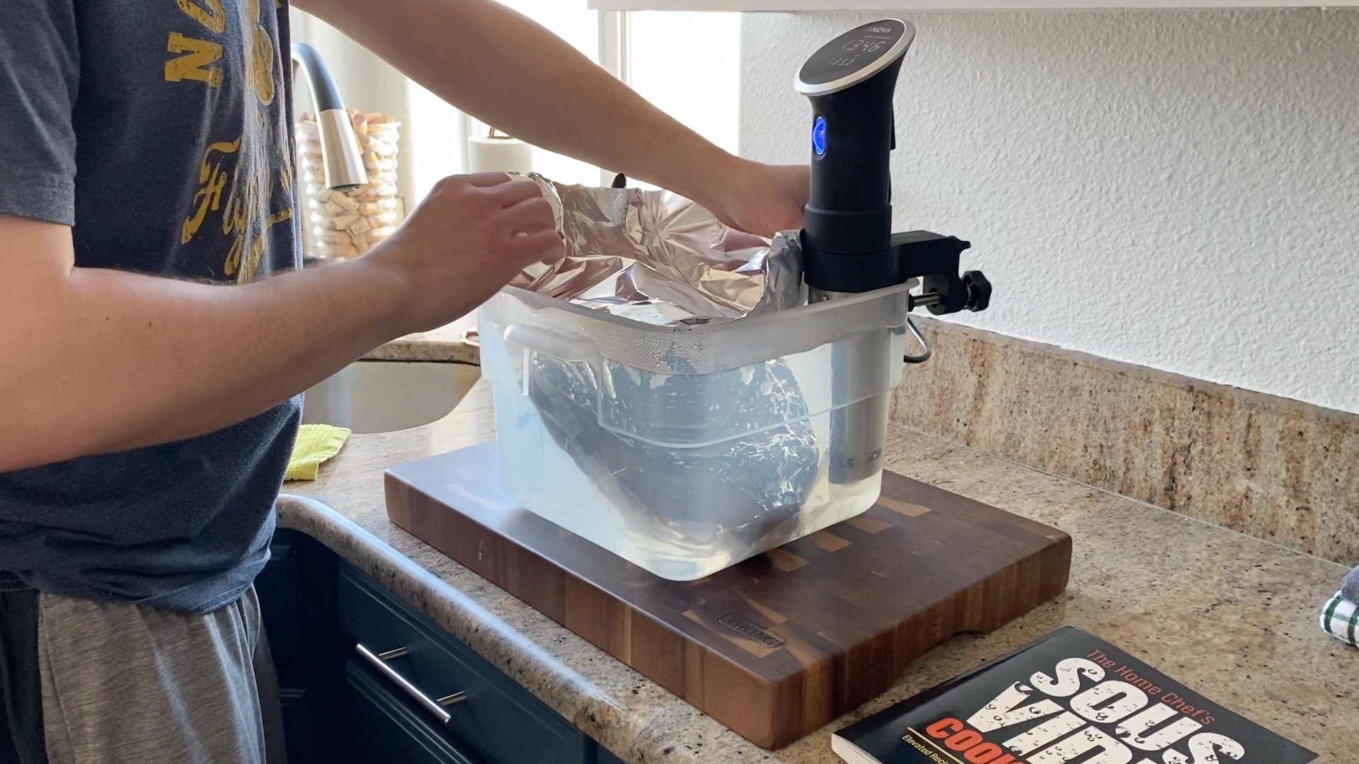 adding seared brisket to sous vide bath with anova precision cooker and viking cutting board in a cambro container