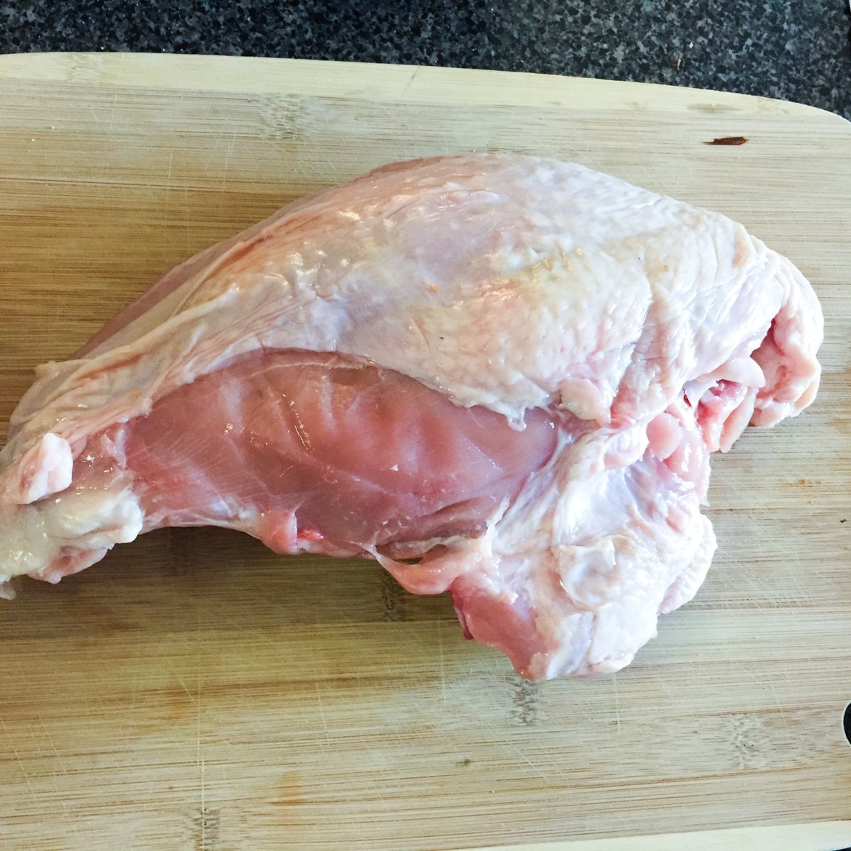 Frozen turkey breast on wood cutting board.