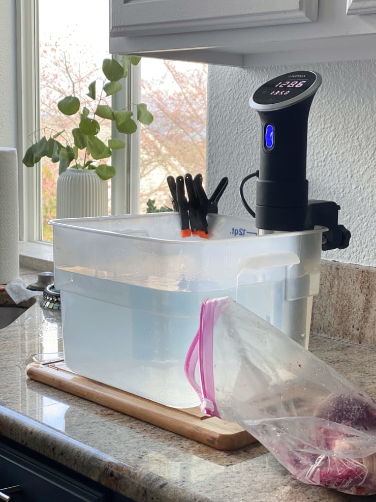 setting up sous vide cooking recipe with a container of water and a sous vide machine