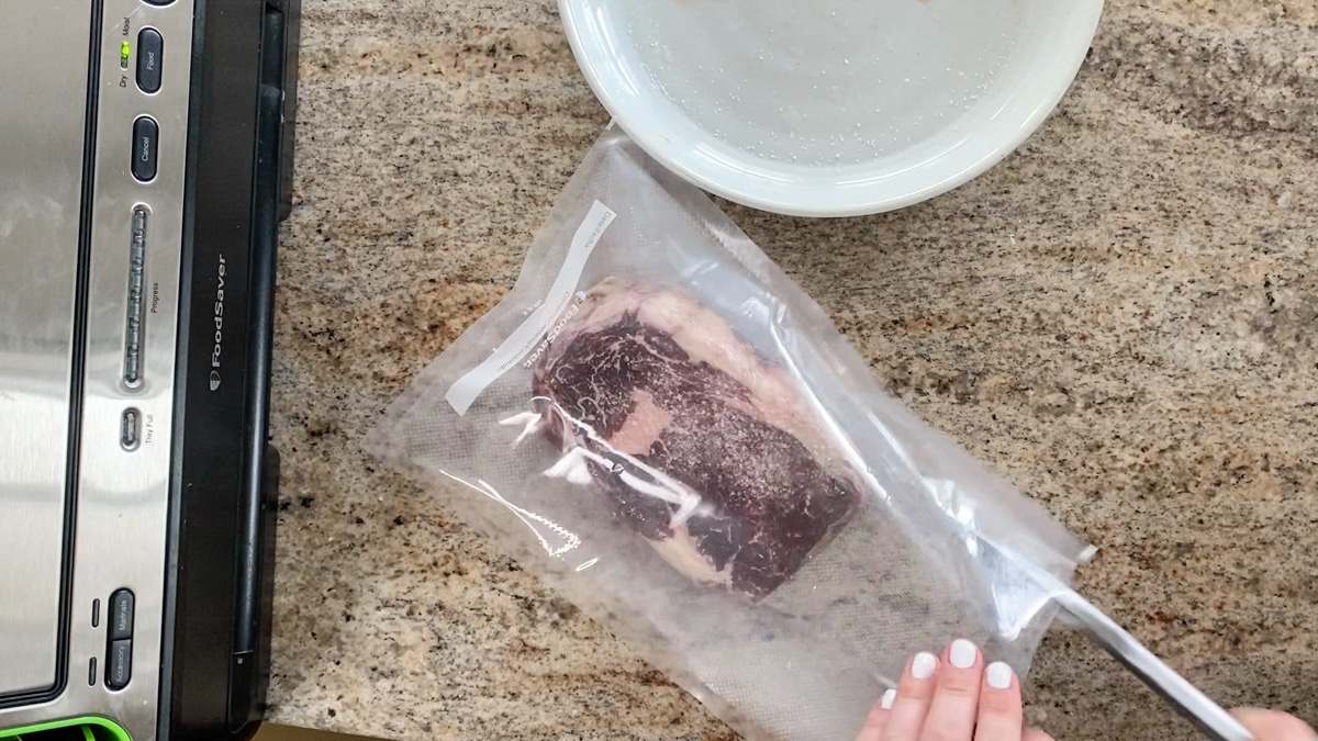 adding steak to vacuum sealed bag with seasonings