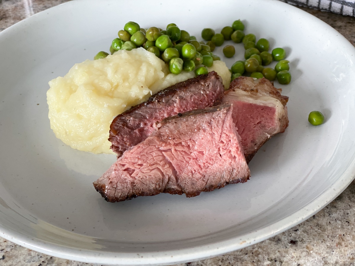 Sous vide New York strip steak dinner with potatoes and peas