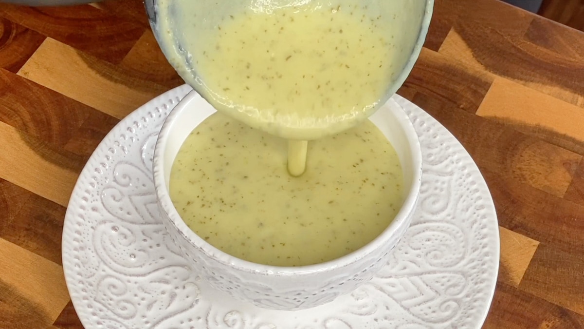 pouring pureed chilled zucchini soup in a bowl