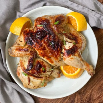 serving sous vide roast chicken on a plate with oranges feature