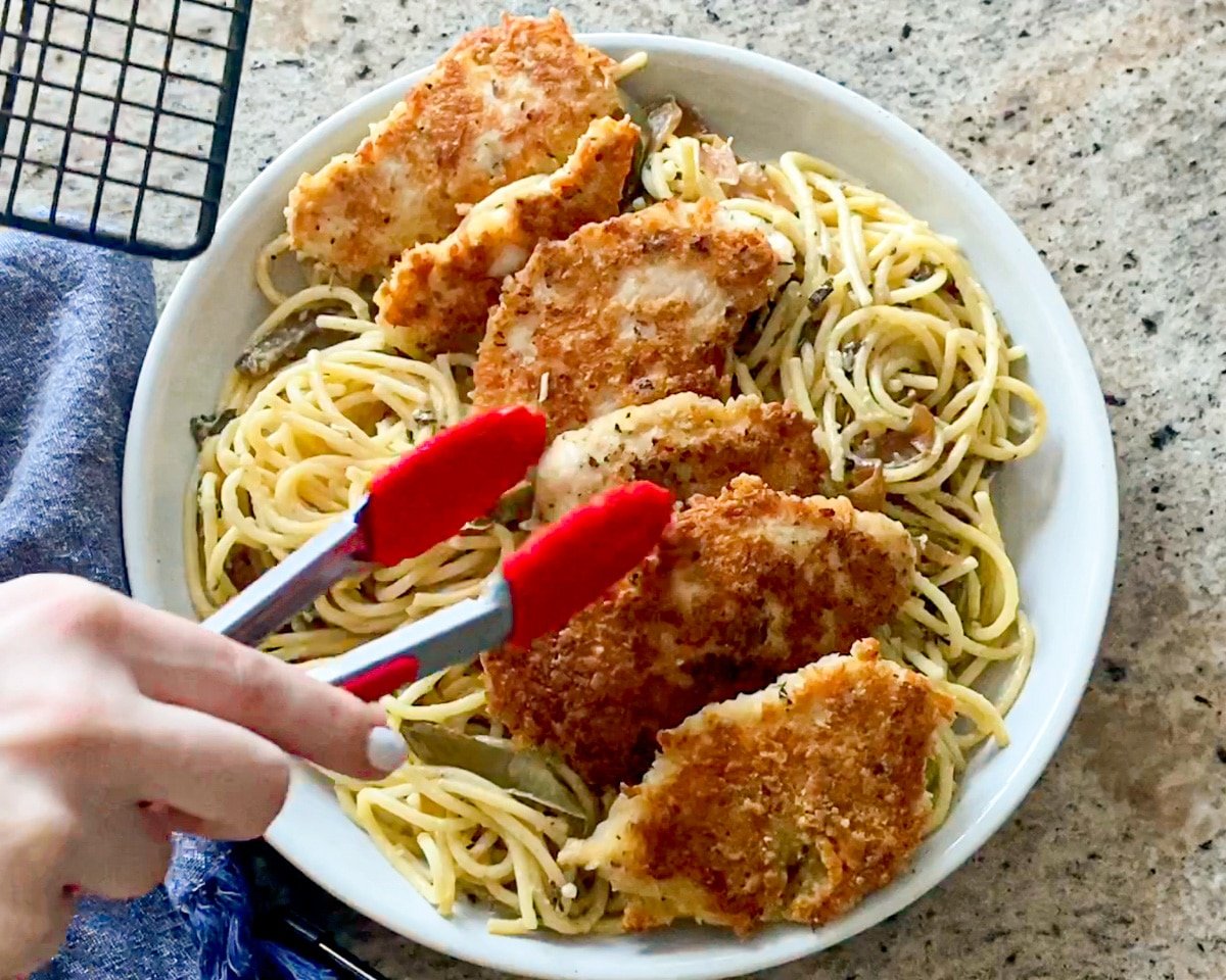 adding chicken to alfredo pasta dish