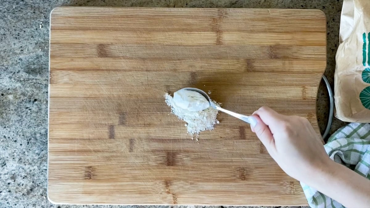 adding flour to cutting board for stretching pizza dough