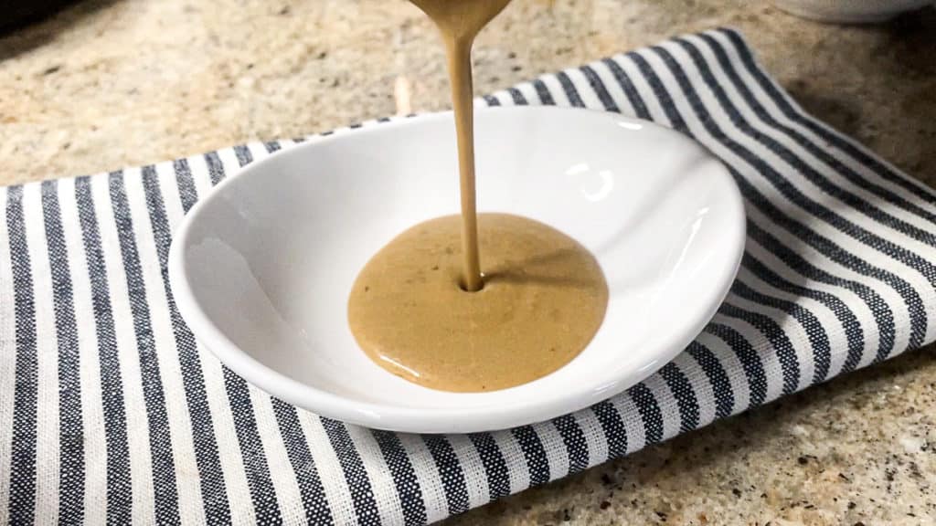 pouring peppercorn sauce into a sauce dish