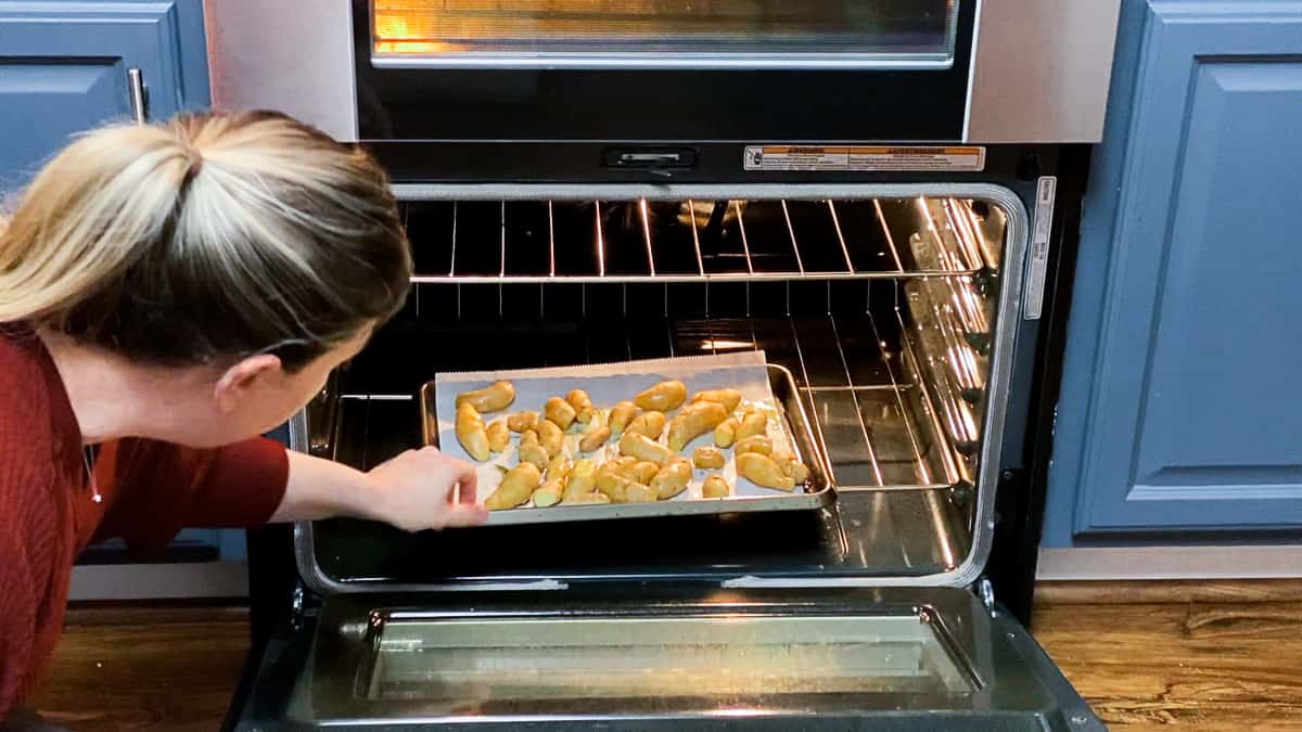 woman placing sous vide fingerling potatoes on baking sheet into oven