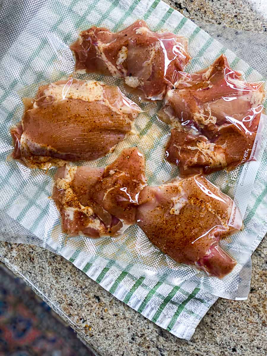 vacuum sealed boneless chicken thighs portioned for meal prep on a kitchen towel