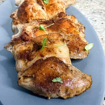 Crispy Sous Vide Boneless Chicken Thighs on a plate with fresh herbs