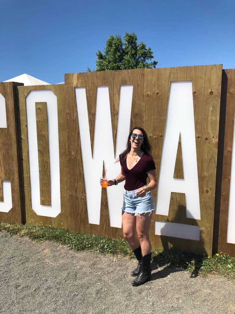 smiling woman with drink in hand in front of a tall sign