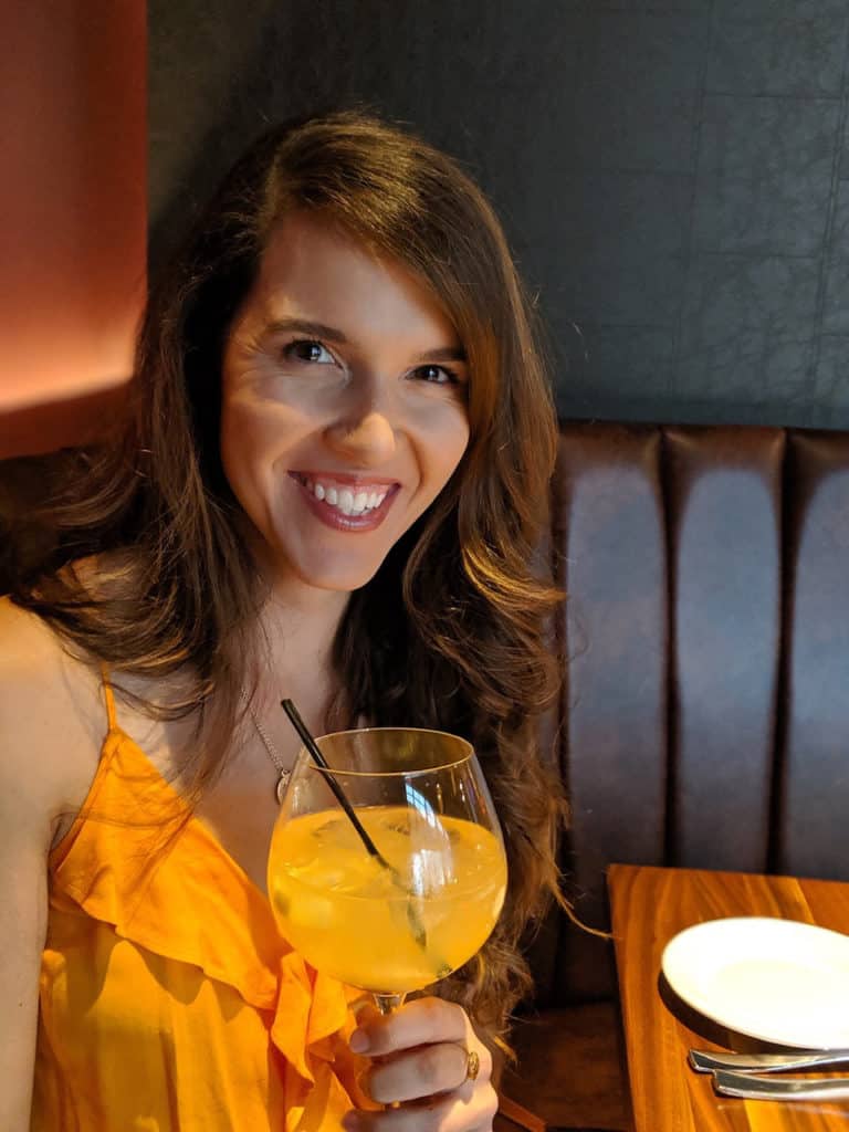 smiling woman in a restaurant booth holding a drink with a straw in it