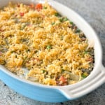 Top shot of potato and vegetable casserole topped with grated cheese in white casserole dish.