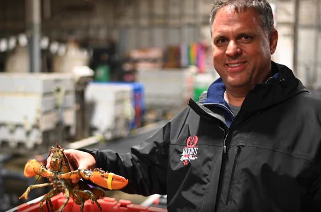 man smiling holding a lobster