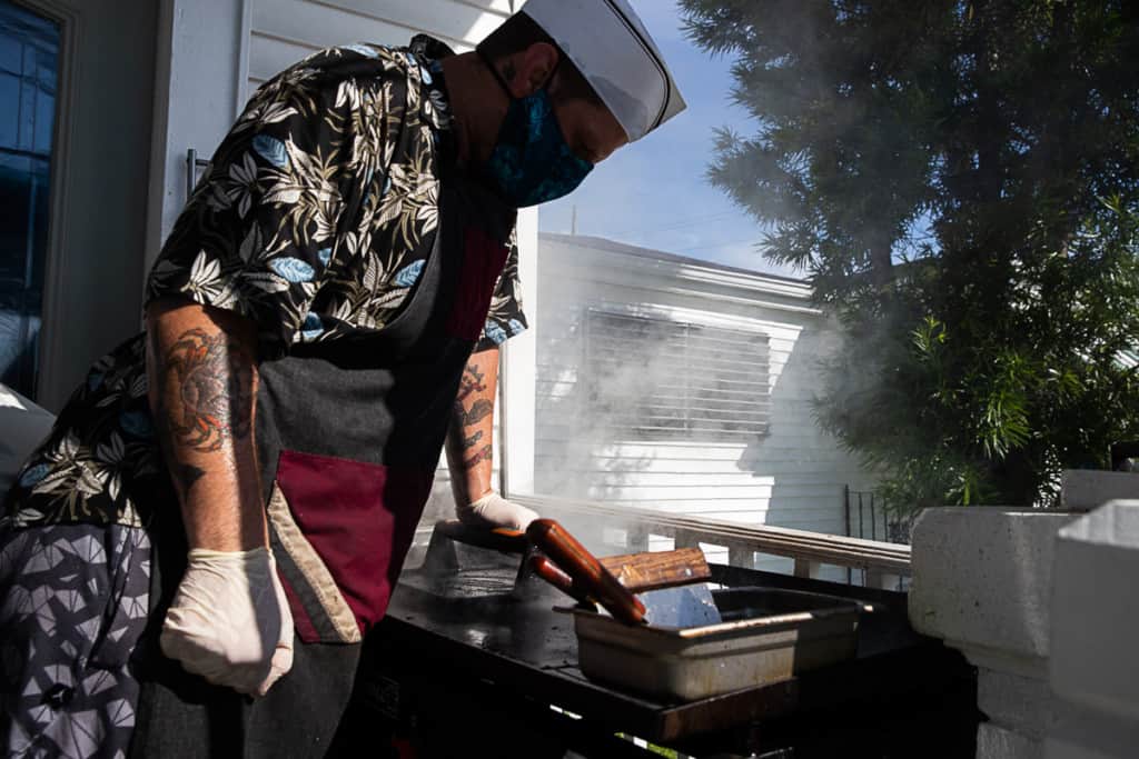 man smashing burger patties on the griddle