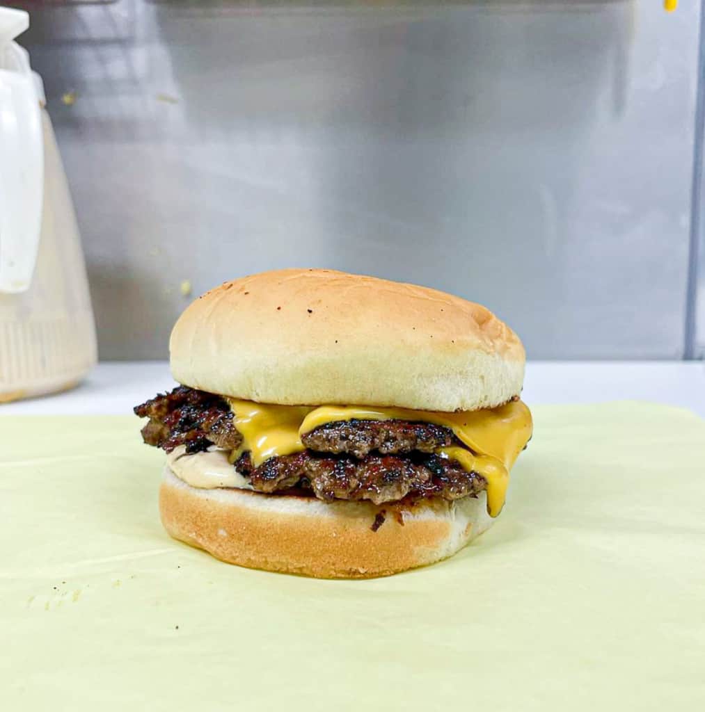 a double stacked burger with cheese and sauce on a white bread bun