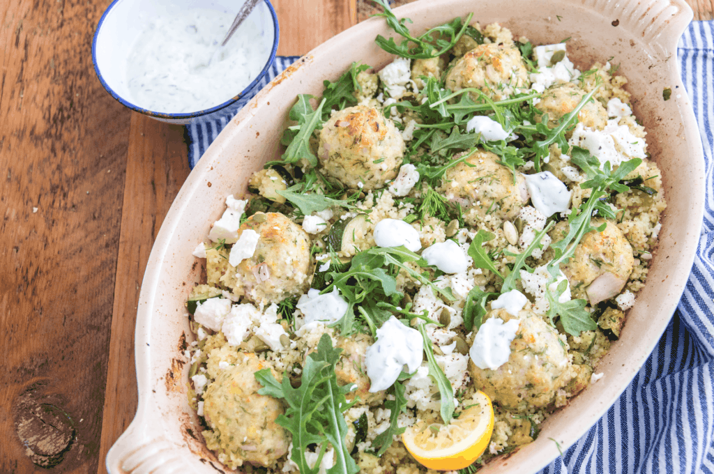 meatballs with arugula and tzatziki in a ceramic baking dish